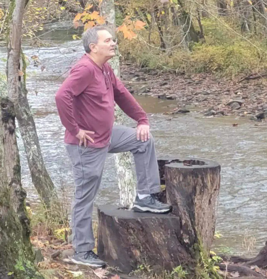 A man standing on top of a tree stump.